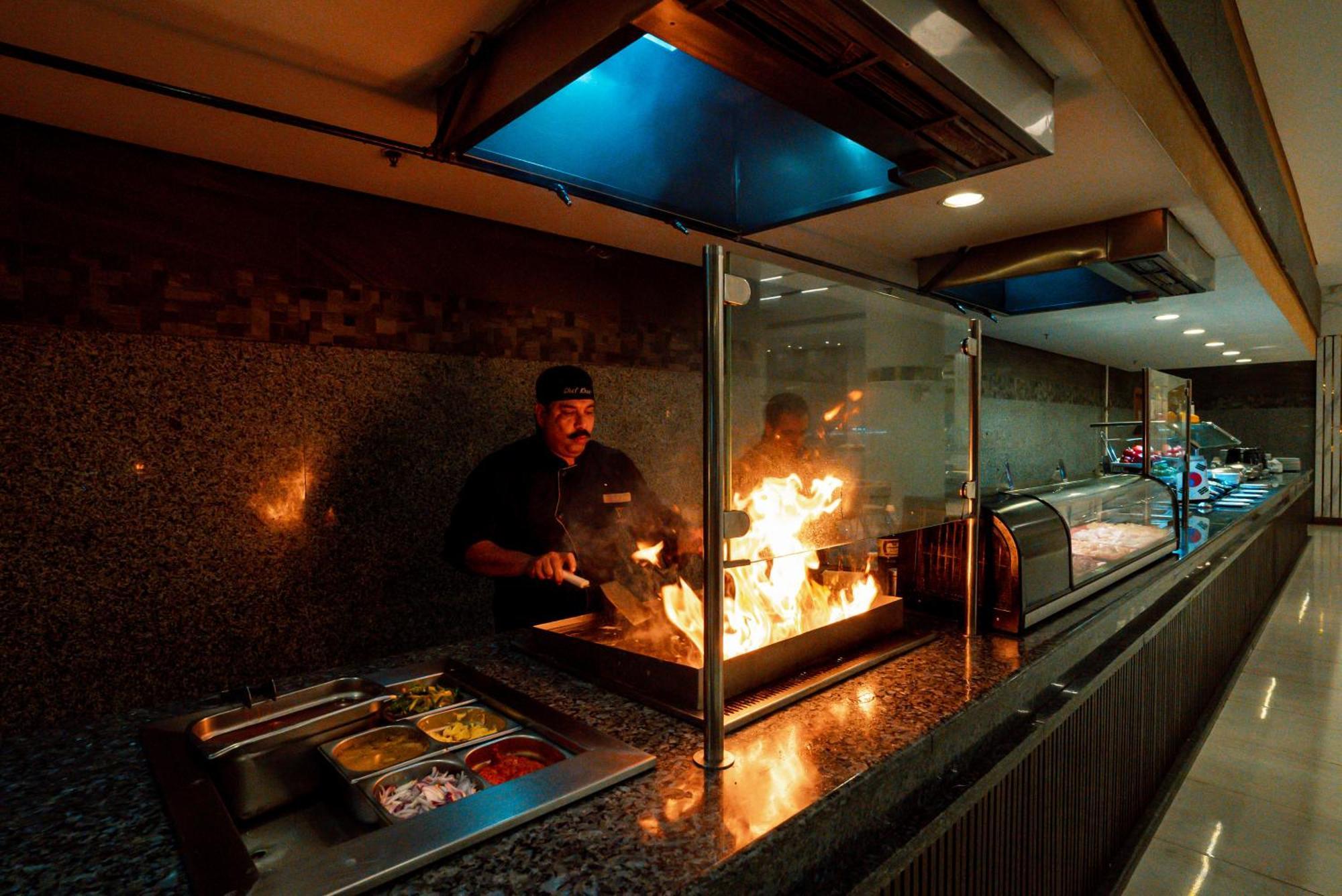 The V Luxury Resort Sahl Hasheesh الغردقة المظهر الخارجي الصورة A chef cooking with a flaming torch
