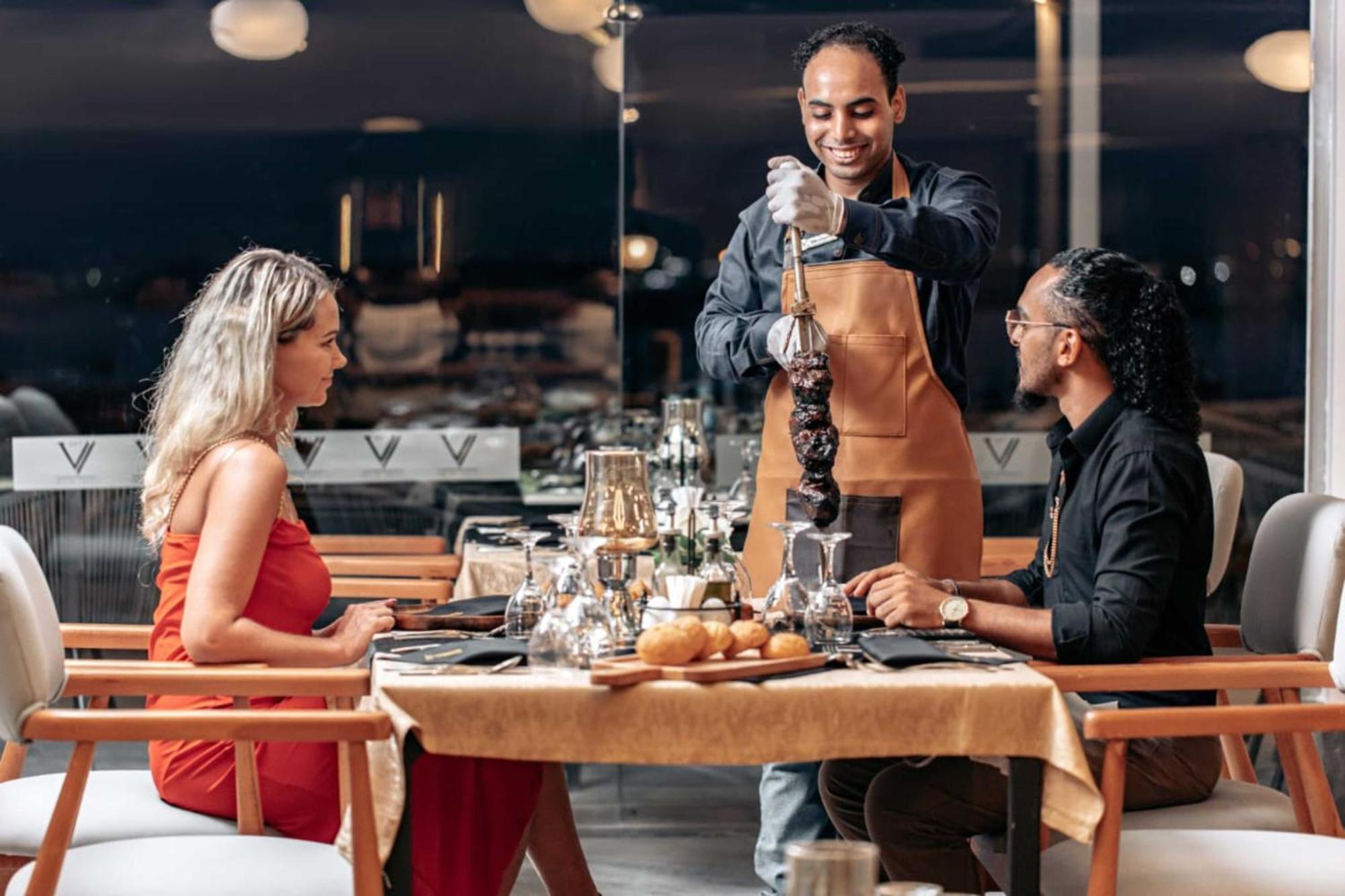 The V Luxury Resort Sahl Hasheesh الغردقة المظهر الخارجي الصورة A waiter serving a couple at a restaurant